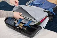 A person places a laptop into the Delsey Paris Cruise 3.0 2-Wheeled Underseater