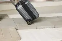 A person wheels the Delsey Paris Cruise 3.0 2-Wheeled Underseater over stone pavers