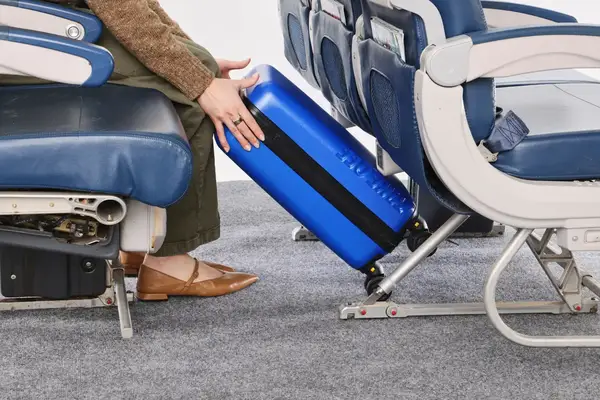 A person places the Take OFF Luggage Personal Item Suitcase 3.0 under an airplane seat