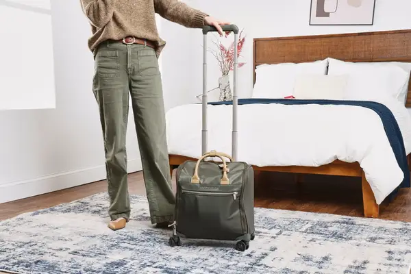 A person wheels the Briggs & Riley Rhapsody Wheeled Cabin Bag over carpet