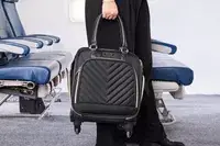 A person carries the Kenneth Cole Reaction Chelsea Luggage Expandable Underseater Spinner by the top handles
