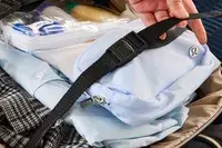 A person touches the strap on the Kenneth Cole Reaction Chelsea Luggage Expandable Underseater Spinner