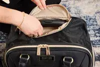 A person raises the handle on the Kenneth Cole Reaction Chelsea Luggage Expandable Underseater Spinner
