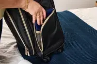 A person places an item into the Kenneth Cole Reaction Chelsea Luggage Expandable Underseater Spinner pocket