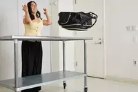 A person throws the Kenneth Cole Reaction Chelsea Luggage Expandable Underseater Spinner off of a metal table