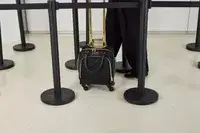 A person wheels the Kenneth Cole Reaction Chelsea Luggage Expandable Underseater Spinner across a smooth floor