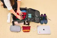 A person packing the Calpak Luka Soft-sided Mini Carry-on Luggage