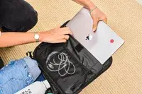 A person placing their laptop into the sleeve of the Calpak Luka Soft-sided Mini Carry-on Luggage