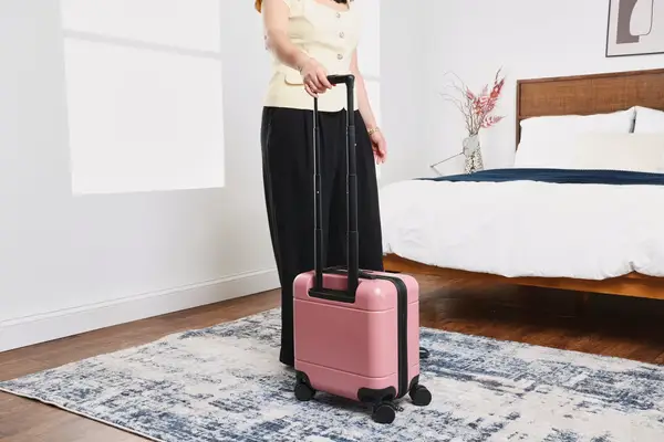 A person wheels the Calpak Hue Mini Carry-on Luggage over a rug