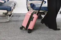 A person wheels the Calpak Hue Mini Carry-on Luggage over carpet