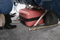 The Calpak Hue Mini Carry-on Luggage under an airplane seat