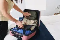 A person packs items into the Calpak Hue Mini Carry-on Luggage