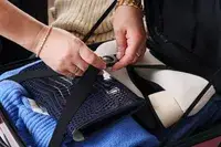 A person secures clothing and shoes in the Calpak Hue Mini Carry-on Luggage