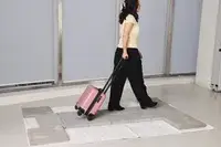 A person wheels the Calpak Hue Mini Carry-on Luggage over stone pavers