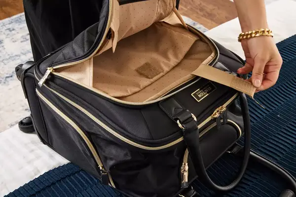 A person examines inside the Kenneth Cole Reaction Chelsea Luggage Expandable Underseater Spinner pocket