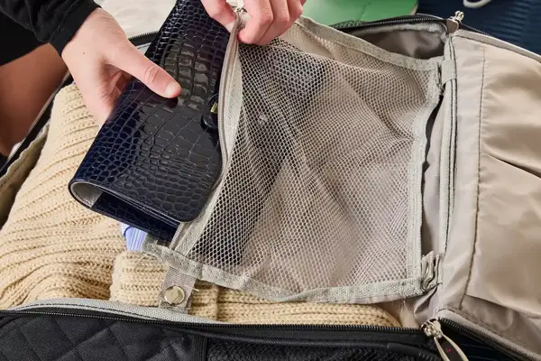 A person places a travel item into the Rockland Melrose Upright Wheeled Underseater Luggage