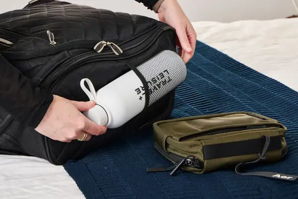 A person places a water bottle into the Rockland Melrose Upright Wheeled Underseater Luggage side pocket