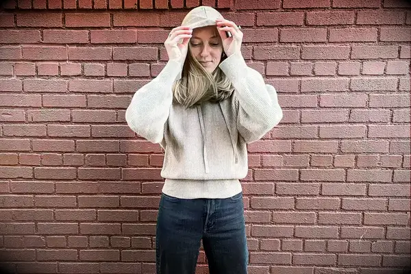 A woman putting on the hood of the Lilysilk Eshe 2-in-1 Cashmere Detachable Hoodie