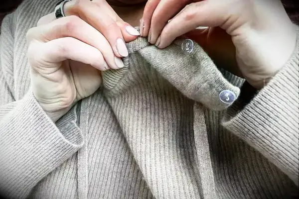 a woman adding on the hood of the Lilysilk Eshe 2-in-1 Cashmere Detachable Hoodie