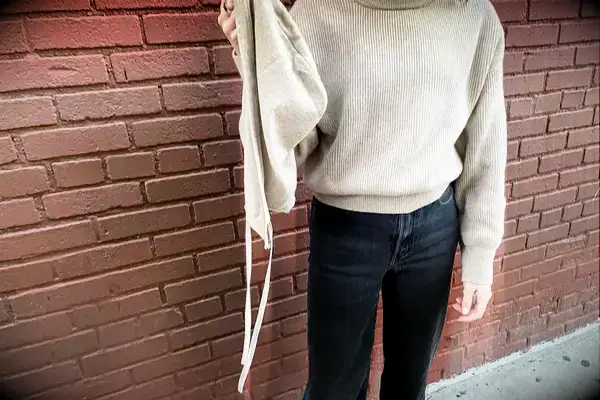 A woman holding the hood of the Lilysilk Eshe 2-in-1 Cashmere Detachable Hoodie