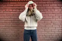 A woman putting on the hood of the Lilysilk Eshe 2-in-1 Cashmere Detachable Hoodie