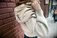 A woman putting on the hood of the Lilysilk Eshe 2-in-1 Cashmere Detachable Hoodie