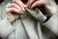 a woman adding on the hood of the Lilysilk Eshe 2-in-1 Cashmere Detachable Hoodie