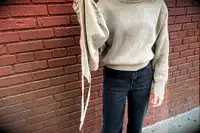 A woman holding the hood of the Lilysilk Eshe 2-in-1 Cashmere Detachable Hoodie