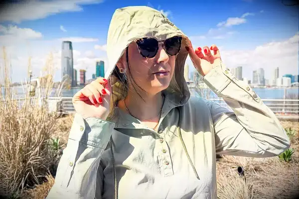 A woman pulling up the hood of the Hikerkind Trail Sun Hoodie 01