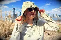 A woman pulling up the hood of the Hikerkind Trail Sun Hoodie 01