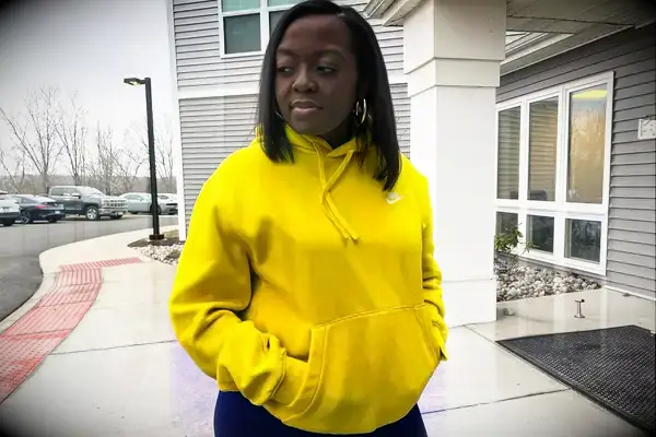 Woman stands outside wearing a Nike Sportswear Club Fleece Pullover Hoodie