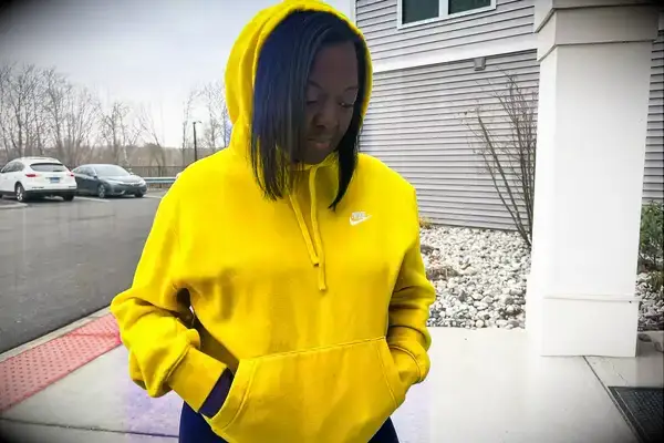 Woman looks down while wearing a Nike Sportswear Club Fleece Pullover Hoodie