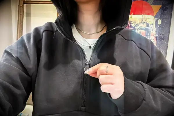 A person pulling the zipper on the Athleta Easy Fleece Half Zip Hoodie