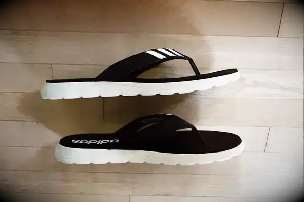 Adidas Comfort Flip-Flops on a wood floor