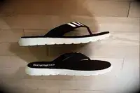 Adidas Comfort Flip-Flops on a wood floor