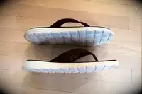 Adidas Comfort Flip-Flops on a wood floor with soles visible