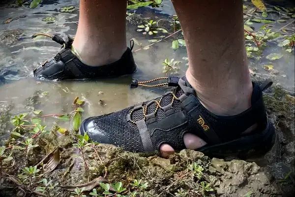 Person wearing Teva Men’s Outflow CT Sandals in muddy water