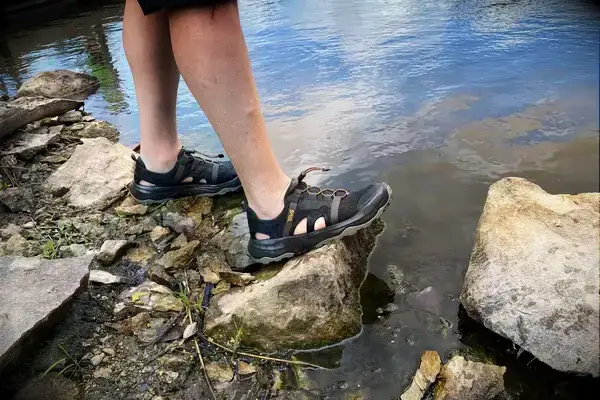 Person wearing Teva Men’s Outflow CT Sandals on rocks in water