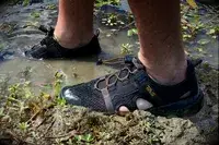 Person wearing Teva Men’s Outflow CT Sandals in muddy water