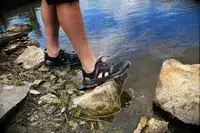 Person wearing Teva Men’s Outflow CT Sandals on rocks in water