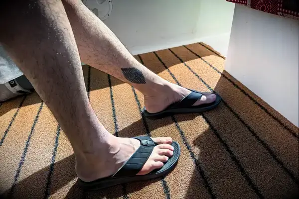 A person wears the Reef The Deckhand sandals on an outdoor rug