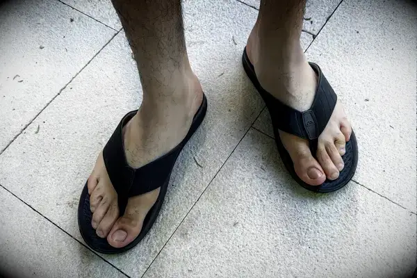 A person wears the Reef The Deckhand sandals on tile