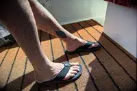 A person wears the Reef The Deckhand sandals on an outdoor rug