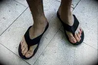 A person wears the Reef The Deckhand sandals on tile