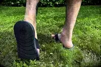 A person walks through grass while wearing the Reef The Deckhand sandals