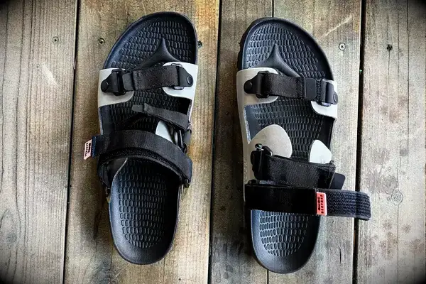 Quoc x Restrap Sandals with adjustable black straps on a wooden surface