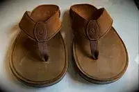 Olukai Tuahine Flip Flop displayed on white desk