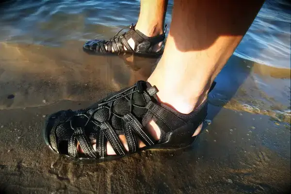 A close up of a person wearing the KEEN Men’s Hyperport H2 Sandal in a beach