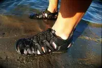 A close up of a person wearing the KEEN Men’s Hyperport H2 Sandal in a beach