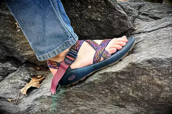 A person wearing the Chacos Z Cloud Sandal standing on a rock